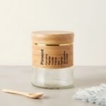 Apportez une touche d'élégance naturelle à votre cuisine avec ce superbe pot à épices en verre, rehaussé de délicates finitions en bois et d'un élégant liseré doré. Pratique et esthétique, il arbore une liste de condiments joliment imprimée et s'accompagne de sa petite cuillère en bois assortie pour un dosage facile de vos saveurs. Idéal pour conserver vos épices tout en sublimant votre plan de travail, ce bocal au design épuré est l'accessoire parfait pour une cuisine à la fois moderne, chaleureuse et parfaitement organisée.
