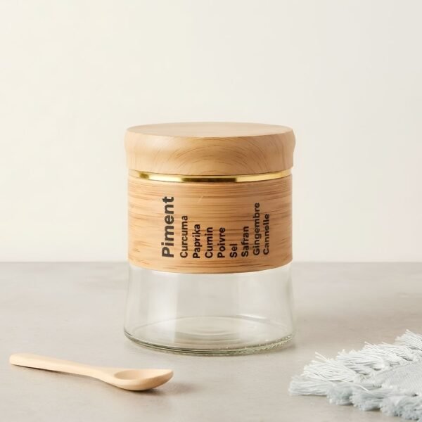 Apportez une touche d'élégance naturelle à votre cuisine avec ce superbe pot à épices en verre, rehaussé de délicates finitions en bois et d'un élégant liseré doré. Pratique et esthétique, il arbore une liste de condiments joliment imprimée et s'accompagne de sa petite cuillère en bois assortie pour un dosage facile de vos saveurs. Idéal pour conserver vos épices tout en sublimant votre plan de travail, ce bocal au design épuré est l'accessoire parfait pour une cuisine à la fois moderne, chaleureuse et parfaitement organisée.